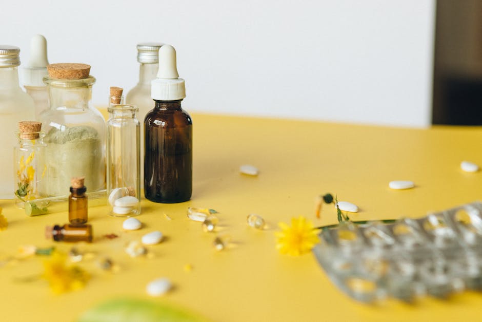 Frascos de vidrio, goteros y pastillas sobre superficie amarilla con flores